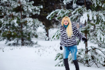 Fototapeta na wymiar beautiful young blond woman in a winter park. Snow-covered trees