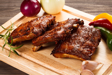 Barbecued ribs with vegetables on cutting board