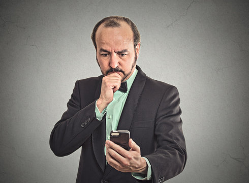 confused business man looking on smartphone thinking on reply