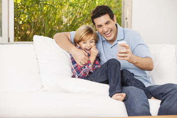 Vater und Sohn auf dem Sofa, machen Selfies