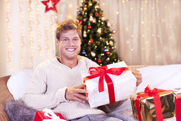 Obraz na płótnie Canvas Glücklicher junger Mann mit Geschenken an Weihnachten