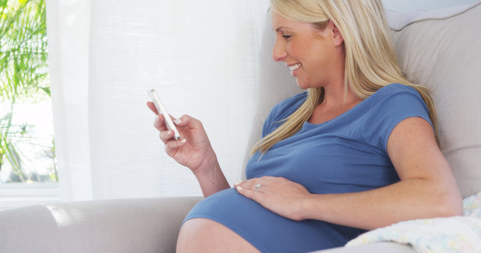 Beautiful pregnant woman texting on smartphone