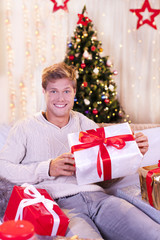 Obraz na płótnie Canvas Glücklicher junger Mann mit Geschenken an Weihnachten