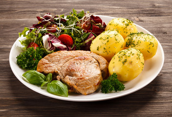 Fried pork chop, boiled potatoes and vegetable salad