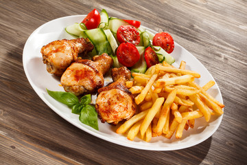 Grilled chicken legs with chips and vegetables