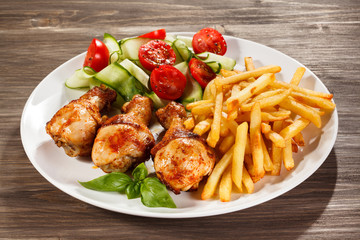 Grilled chicken legs with chips and vegetables