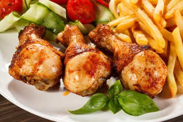 Grilled chicken legs with chips and vegetables