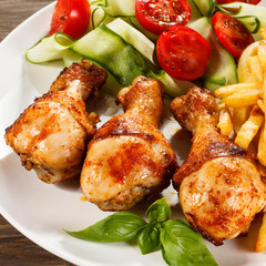 Grilled chicken legs with chips and vegetables
