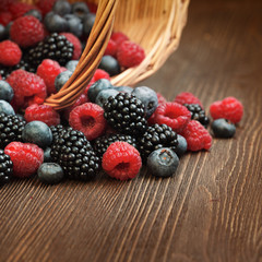 different berries in a basket on a wooden table