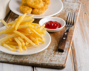 French fries and chicken nuggets on  a wooden board