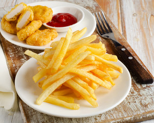 fries and chicken nuggets on   wooden table