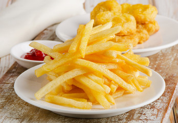 French fries and chicken nuggets on  wooden board