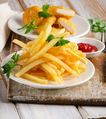 French fries and chicken nuggets on  a wooden table
