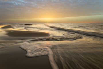 fale przelewający się na plaży morskiej podczas zachodu słońca - obrazy, fototapety, plakaty