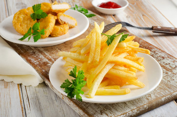 French fries and chicken nuggets on   wooden table