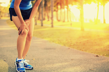 woman runner hold her sports injured legs