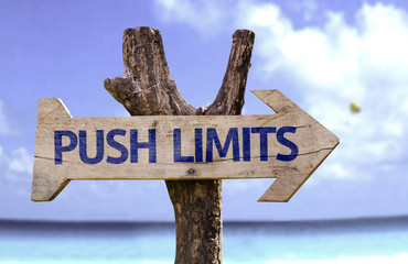 Push Limits wooden sign with a beach on background