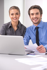 Fototapeta premium Cheerful business people sitting at table with laptop.