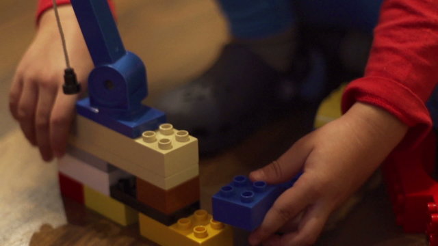 Young child connecting blocks, closeup, steadycam, slow motion