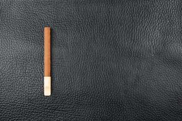 Cigar with a wooden mouthpiece lies on genuine leather