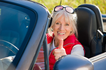 Seniorin im Cabriolet mit Daumen nach oben