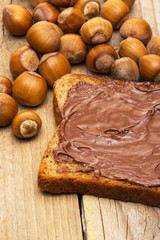 Bread with sweet chocolate hazelnut spread on wooden background