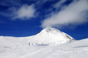 Fototapeta na wymiar Chair-lift and ski slope at sun wind day
