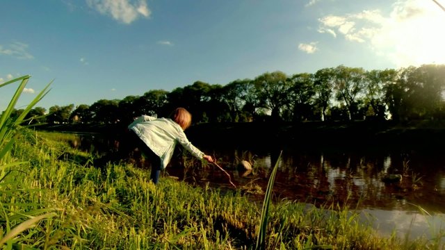 ittle girl weaves a wreath of grass on the field