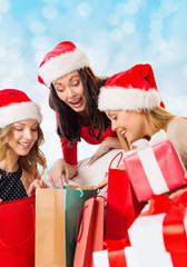 smiling young women in santa hats with gifts