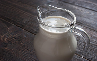 A glass picher with milk on the wooden table