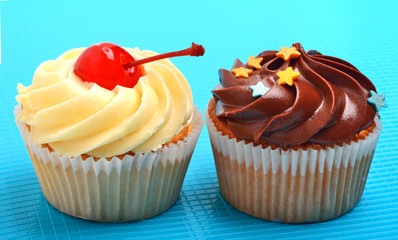Delicious chocolate and creamy muffins on blue background