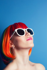 beautiful woman wearing colorful wig and white sunglasses agains