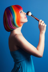 Obraz premium beautiful woman wearing colorful wig and holding make-up brush a