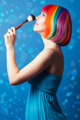 Obraz premium beautiful woman wearing colorful wig and holding make-up brush a