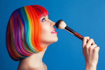 beautiful woman wearing colorful wig and holding make-up brush a