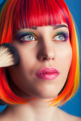 beautiful woman wearing colorful wig and holding make-up brush a