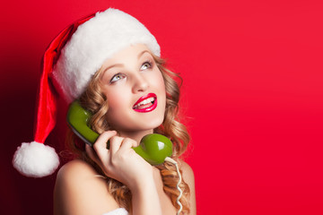 beautiful young woman wearing Santa Claus costume holding green