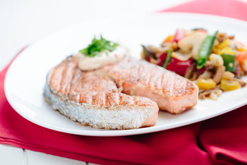 Grilled Salmon with Fresh vegetables on red background