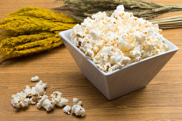 Popcorn in a square shape bowl with crop, rye beside
