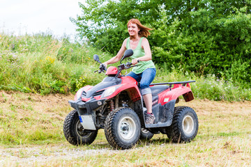 Fototapeta na wymiar Frau fährt Off-Road mit Quad ATV durch Gelände 