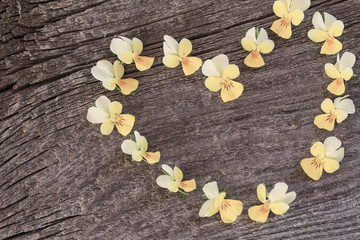 yellow flowers in form heart on wooden background