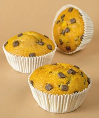 A selection of chocolate chip muffins on a brown background