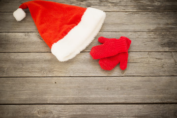 Obraz na płótnie Canvas Santa's hat and red mitten on old wooden background