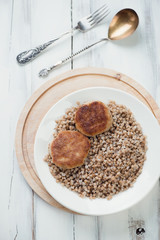 Meat cutlets and buckwheat in a plate, view from above