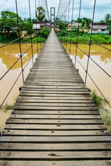 Rope suspension bridge across a river in flood, Thailand