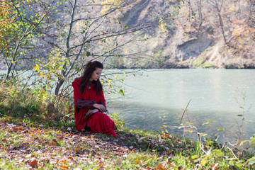 Girl in a red cloak in the lap of nature