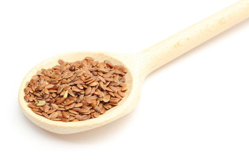 Heap of linseed with wooden spoon on white background