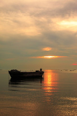 Obraz premium old boat in front of sunset background near beach