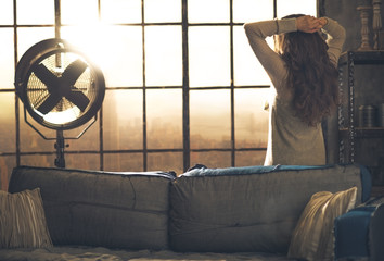 Young woman looking in window in loft apartment. rear view