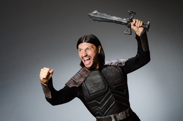 Angry knight with sword against dark background